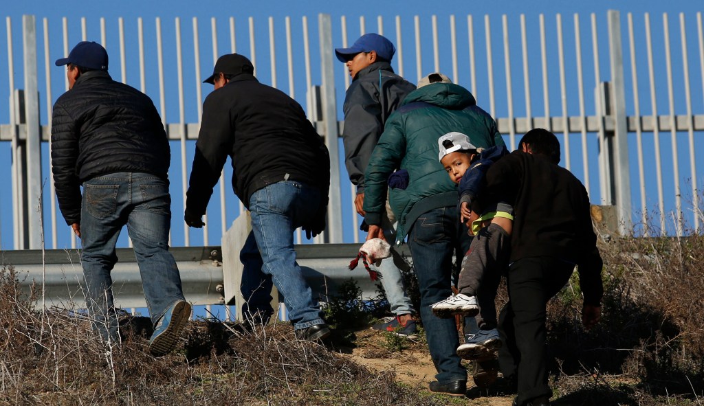 Migrants on Mexico-California border seen wearing shirts begging Biden to let them in