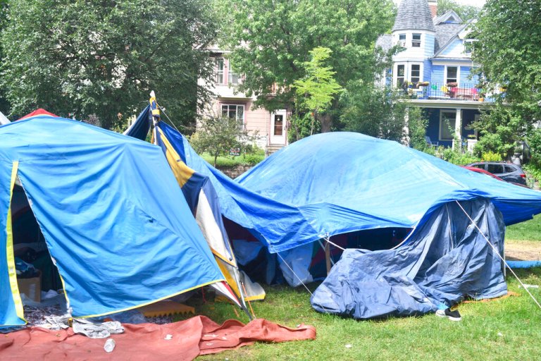 Residential houses are visible Thursday, July 15, 2020 across the street from a homeless encampment at Powderhorn Park in Minneapolis. (AP Photo/Jim Mone)
