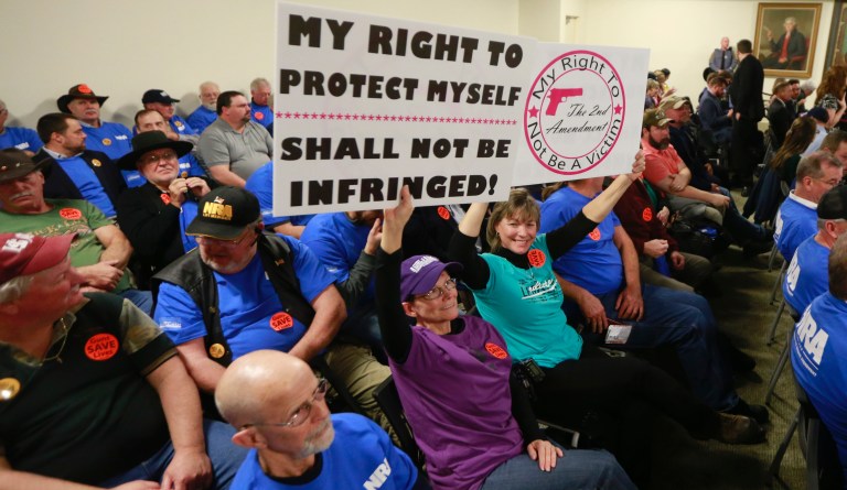 Gun rights protesters hold signs prior to the start of a meeting of the Senate Judiciary committee at the Capitol in Richmond, Va., Monday, Jan. 13, 2020. The Committee passed several bills related to gun laws.