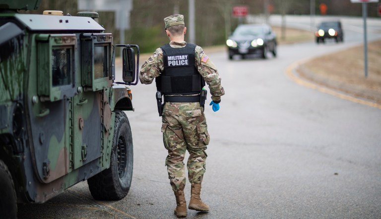 A member of the Rhode Island National Guard Military Police directs motorists with New York license plates at a checkpoint on I-95 over the border with Connecticut where New Yorkers must pull over and provide contact information and are told to self-quarantine for two weeks, Saturday, March 28, 2020, in Hope Valley, R.I. Rhode Island Gov. Gina Raimondo on Saturday ordered anyone visiting the state to self-quarantine for 14 days and restricted residents to stay at home and nonessential retail businesses to close Monday until April 13 to help stop the spread of the coronavirus. 