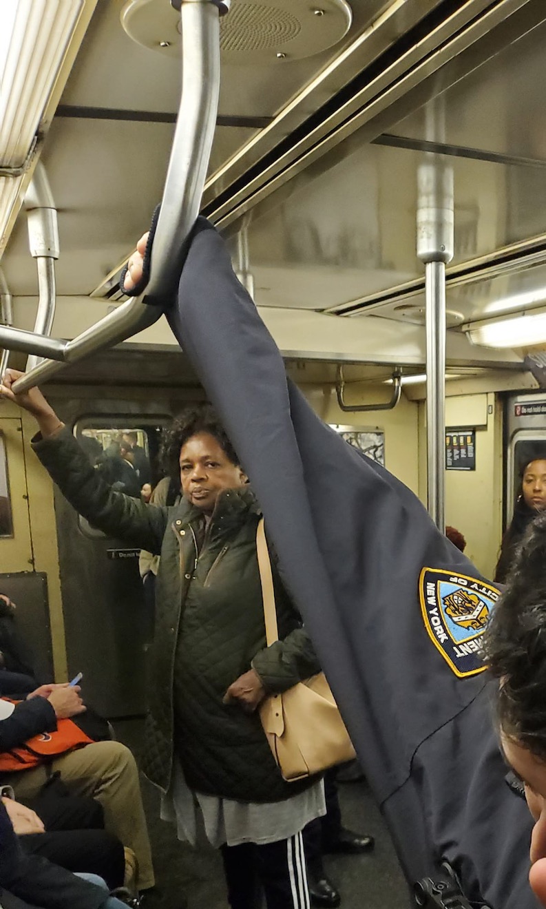 An NYPD officer (pictured in the front) rides the subway without protective gear.