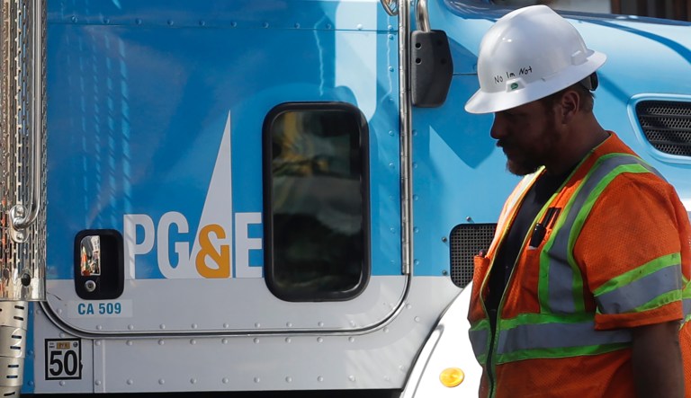 A Pacific Gas & Electric worker walks in front of a truck in San Francisco, Thursday, Aug. 15, 2019.  (AP Photo/Jeff Chiu)   