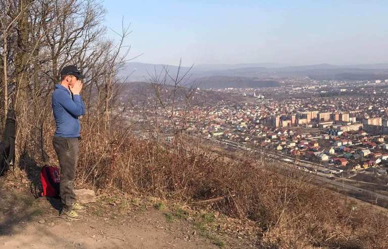 A Ukrainian refugee prays over his land atop a hill in western Ukraine.