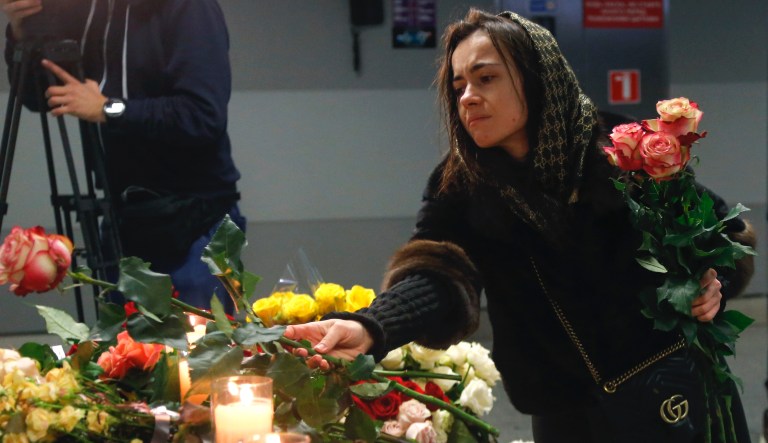 A woman lays flowers at a memorial of the flight crew members of the Ukrainian 737-800 plane that crashed on the outskirts of Tehran, at Borispil international airport outside in Kyiv, Ukraine, Saturday, Jan. 11, 2020. Ukraine's President Volodymyr Zelenskiy says that Iran must take further steps following its admission that one of its missiles shot down Ukrainian civilian airliner. He also expressed hope for the continuation of the crash investigation without delay. A team of Ukrainian investigators is in Iran.