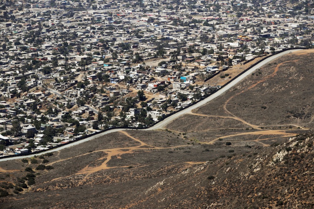 A road runs alongside a border wall that separates Tijuana, Mexico, top, from San Diego. A congressional watchdog agency says the Trump administration's plan to erect hundreds of miles of barriers along the border with Mexico fails to adequately consider costs, potentially raising the price and creating delays. The Government Accountability Office said that costs can vary considerably based on the slope and topography, land acquisition costs and other factors.