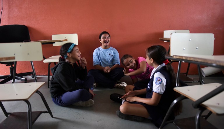 In this Oct. 13, 2017, photo, youths chat at the Ramon Marin Sola Elementary School, which opened its doors as a daytime community center after the passing of Hurricane Maria in Guaynabo, Puerto Rico.