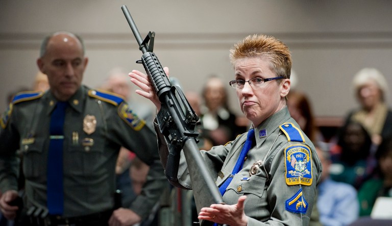 In this Jan. 28, 2013, file photo, firearms training unit Detective Barbara J. Mattson, of the Connecticut State Police, holds a Bushmaster AR-15 rifle, the same make and model used by Adam Lanza in the 2012 Sandy Hook School shooting, during a hearing at the Legislative Office Building in Hartford, Conn.