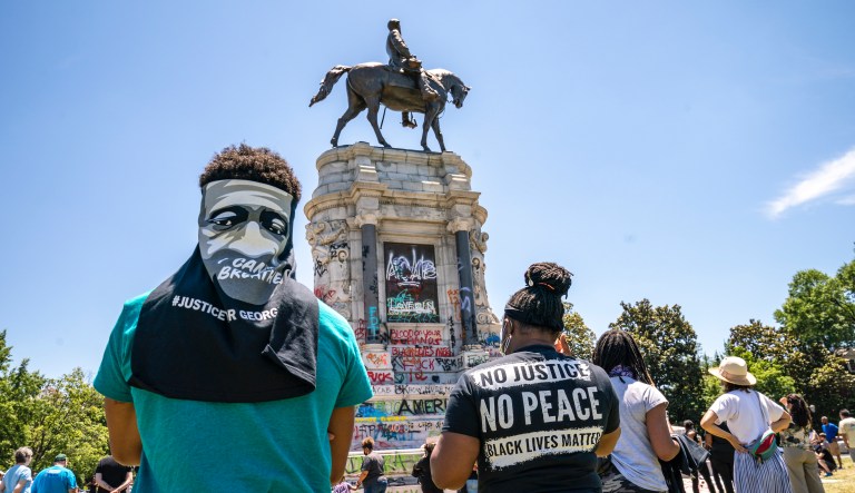 People gather at the Robert E. Lee Monument, now covered by protest graffiti, in Richmond, Virginia.