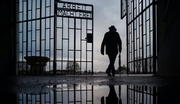 In this Sunday, Jan. 27, 2019 file photo a man walks through the gate of the Sachsenhausen Nazi death camp with the phrase 'Arbeit macht frei' (work sets you free) during International Holocaust Remembrance Day in Oranienburg, about 30 kilometers (18 miles), north of Berlin, Germany. German prosecutors say they have charged a 100-year-old man with 3,518 counts of accessory to murder on allegations he served as an SS guard at the Nazisâ Sachsenhausen concentration camp on the outskirts of Berlin.