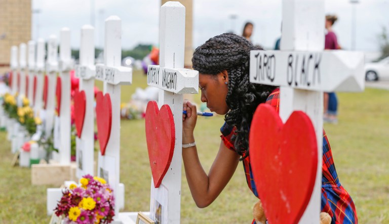 Santa Fe High School freshman, Jai Gillard writes messages on each of the 10 crosses in front the school Monday, May 21, 2018, in Santa Fe. Gillard, was in the art class Friday morning, knew all of the victims of the shooting. Texas Governor Greg Abbott has called for a moment of silence at 10 a.m. and came to the school to participate.