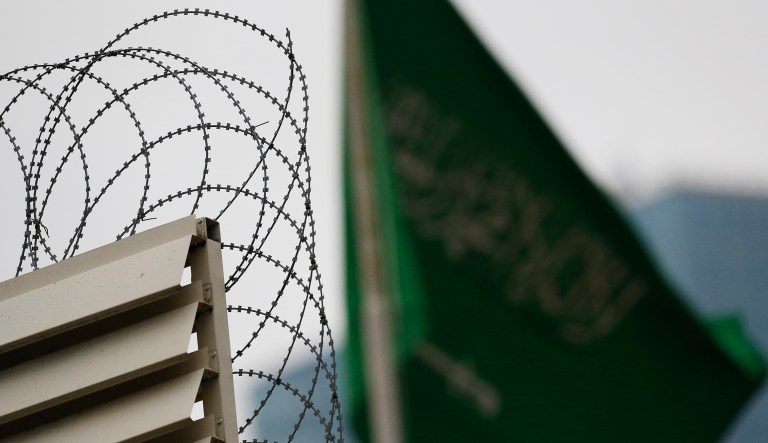 Behind barbed wire, Saudi Arabia's flag flies atop the country's consulate in Istanbul, Thursday, Oct. 18, 2018. Turkish crime-scene investigators finished an overnight search of both residence and a second search of the consulate itself amid Ankara's fears that Saudi writer Jamal Khashoggi was killed and dismembered inside the diplomatic mission in Istanbul.