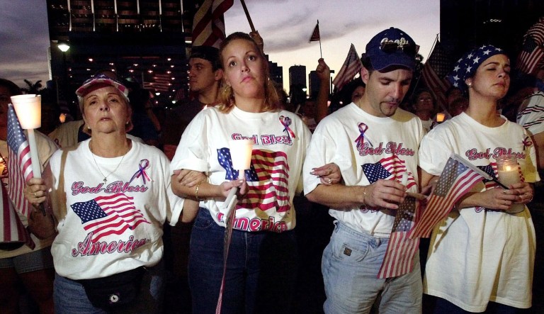 Candlelight vigil participants, from left, Lucia Lopez, Laura Lopez, Richard Lopez and Iliana Leyva, lock arms as a they sing along during an event honoring the victims of Tuesday's terrorist attacks Sunday Sept. 16, 2001, at Bayfront Park in downtown Miami. Over 500 South Floridians gathered at the park for the service.