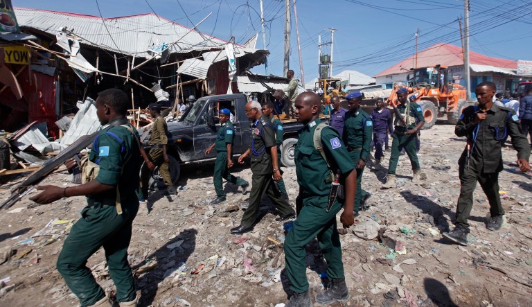 Somali security forces walk past destroyed shops after a car bomb attack at a busy junction in the Wadajir district of the capital Mogadishu, Somalia, Monday, Nov. 26, 2018.