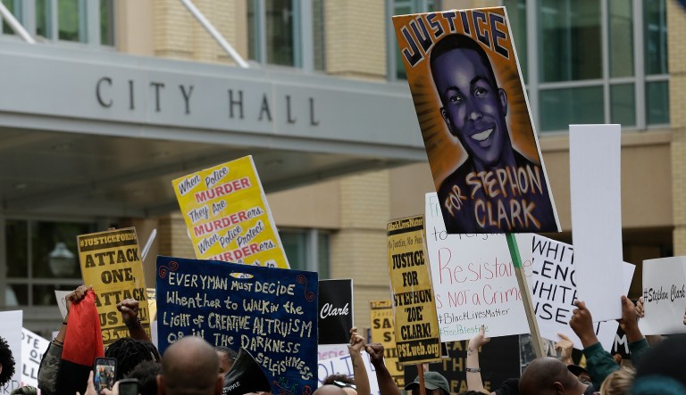 Demonstrators calling for the indictment of two Sacramento police officers who shot and killed Stephon Clark, pass Sacramento City Hall as they march through downtown Sacramento, Calif., Wednesday, April 4, 2018. Clark, who was unarmed, was shot and killed by Sacramento police officers on March 18.
