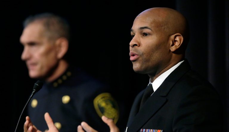 United States Surgeon General Jerome Adams, right, addresses an audience as Arlington, Mass., Police Chief Frederick Ryan, left, looks on Thursday, Dec. 6, 2018, during a national summit focused on police efforts to address the opioid epidemic at Harvard Medical School in Boston. AP Photo/Steven Senne
