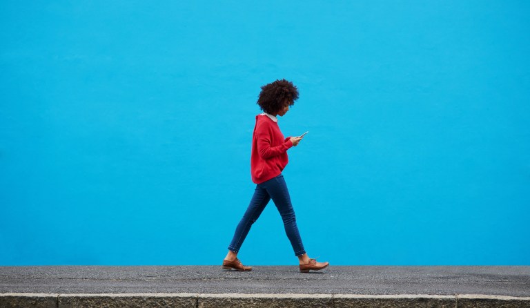 Shot of a fashionable young woman using her cellphone while walking through the city.
