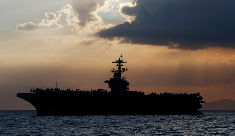 FILE - In this April 13, 2018, file photo the USS Theodore Roosevelt aircraft carrier is anchored off Manila Bay west of Manila, Philippines. The captain of the U.S. Navy aircraft carrier facing a growing outbreak of the coronavirus is asking for permission to isolate the bulk of his roughly 5,000 crew members on shore, which would take the warship out of duty in an effort to save lives. The ship is docked in Guam.