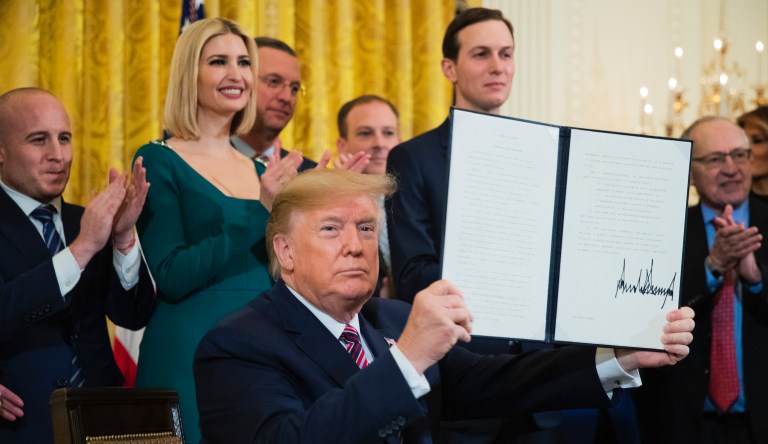 President Donald Trump shows the executive order he signed targeting what his administration says is growing anti-Semitism on U.S. college campuses during a Hanukkah reception in the East Room of the White House in Washington on Wednesday, Dec. 11, 2019.