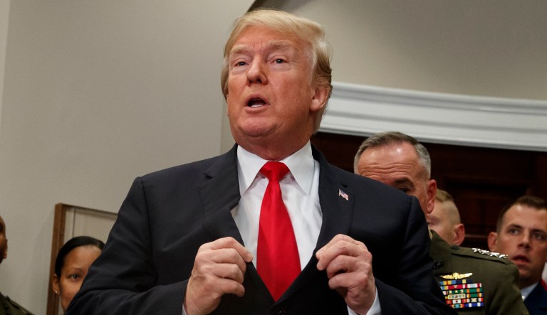 President Donald Trump adjusts his suit jacket after signing the National Defense Authorization Act for Fiscal Year 2018 bill, in the Roosevelt Room of the White House, Tuesday, Dec. 12, 2017, in Washington.