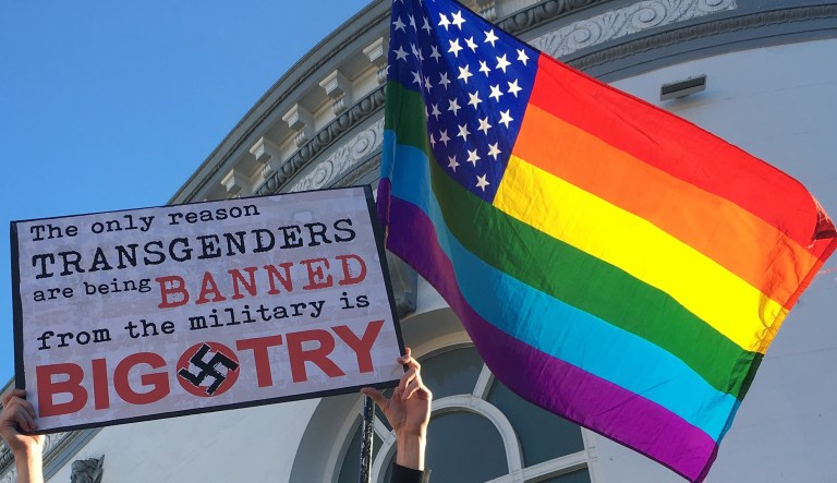 Nick Rondoletto, left, and Doug Thorogood, a couple from San Francisco, wave a rainbow flag and hold a sign against a proposed ban of transgendered people in the military at a protest in the Castro District, Wednesday, July 26, 2017, in San Francisco. Demonstrators flocked to a plaza named for San Francisco gay-rights icon Harvey Milk to protest President Donald Trumpâs abrupt ban on transgender troops in the military.