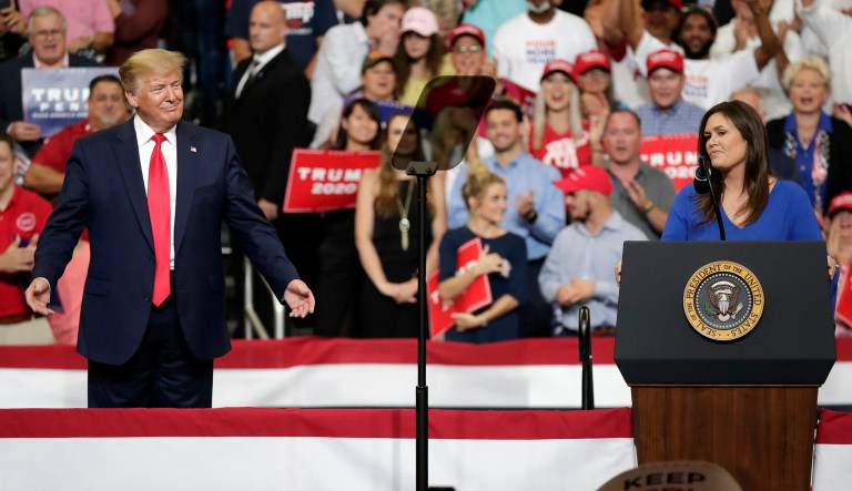 President Donald Trump, smiles as press secretary Sarah Sanders speaks to supporters at a rally where Trump formally announced his 2020 re-election bid Tuesday, June 18, 2019, in Orlando, Fla.