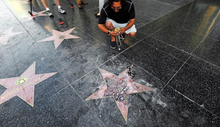 Victor Lomelli of Los Angeles blogs over the vandalized star of Donald Trump on the Hollywood Walk of Fame Wednesday morning, July 25, 2018, in Los Angeles. Authorities say the vandalism was reported around 3:30 a.m. Wednesday and someone was subsequently taken into custody. The star placed on Hollywood Boulevard near Highland Avenue in 2007 recognizes Trump for his work on the reality show "The Apprentice."