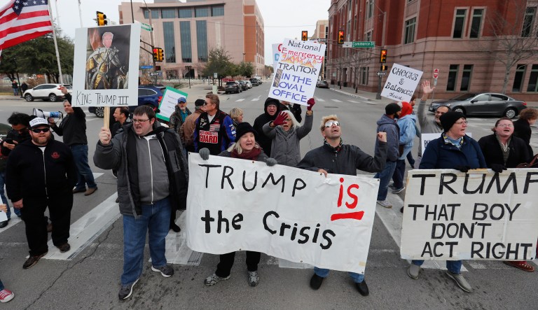 Protesters hold signs in a crosswalk in downtown Fort Worth, Texas, Monday, Feb. 18, 2019.