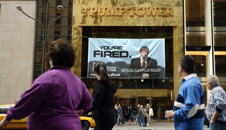 In this March 27, 2004 file photo, passersby look at a sign from Donald Trump's television show, "The Apprentice," hung on the Trump Tower in New York. 
