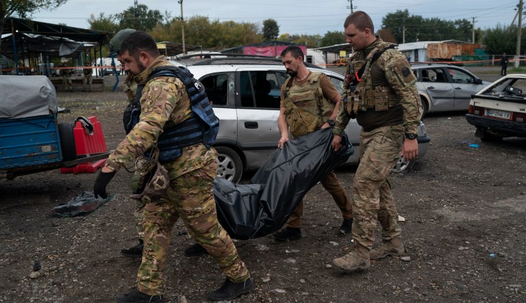 Ukrainian servicemen carry a bag containing the body of a person after a Russian attack in Zaporizhzhia, Ukraine, Friday, Sept. 30, 2022. 