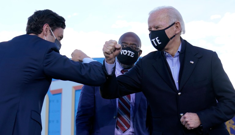 President-elect Joe Biden elbow bumps Senate candidate Jon Ossoff as Senate candidate Raphael Warnock watches in Atlanta, Monday, Jan. 4, 2021, during a campaign rally.