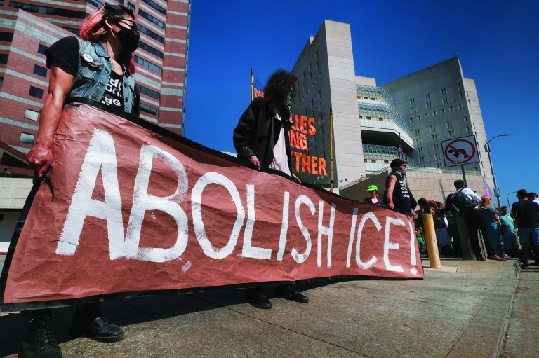 Protesters display a sign that reads "Abolish ICE" during a rally in front of the Immigration and Customs Enforcement facility in downtown Los Angeles on Monday, July 2, 2018. Protesters who were blocking the entrance to an Immigration and Customs Enforcement facility in downtown Los Angeles have been led away in handcuffs. A group of 17 protesters sat down in the street, blocking the entrance to the facility Monday morning. The protesters, including faith and community leaders, locked arms and chanted, "Shut down ICE!" (AP Photo/Richard Vogel)