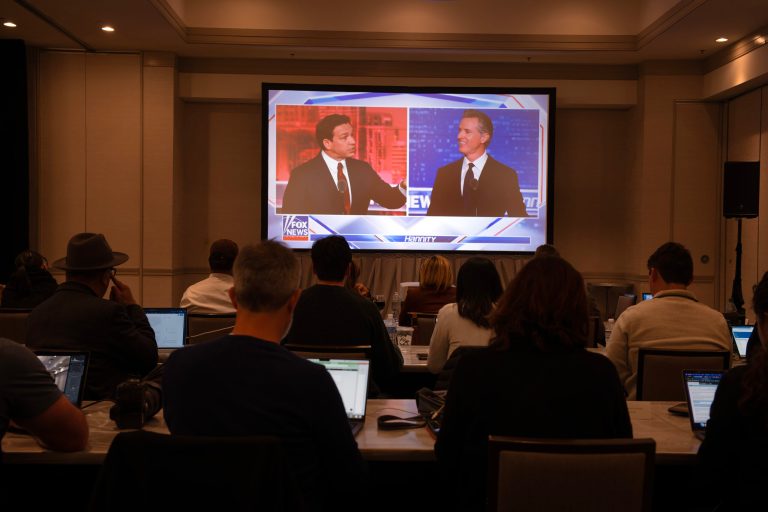 Reporters watch from an off-site hotel as Florida Gov. Ron DeSantis and California Gov. Gavin Newsom debate on Fox News cable channel on November 30, 2023.