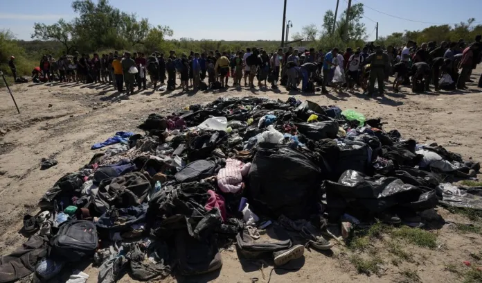 Migrants stands near a pile of discarded items as they wait to be processed by the U.S. Customs and Border Patrol after they crossed the Rio Grande and entered the U.S. from Mexico, Thursday, Oct. 19, 2023, in Eagle Pass, Texas. Starting in March, Texas will give police even broader power to arrest migrants while also allowing local judges to order them out of the U.S. under a new law signed by Republican Gov. Greg Abbott. (AP Photo/Eric Gay)