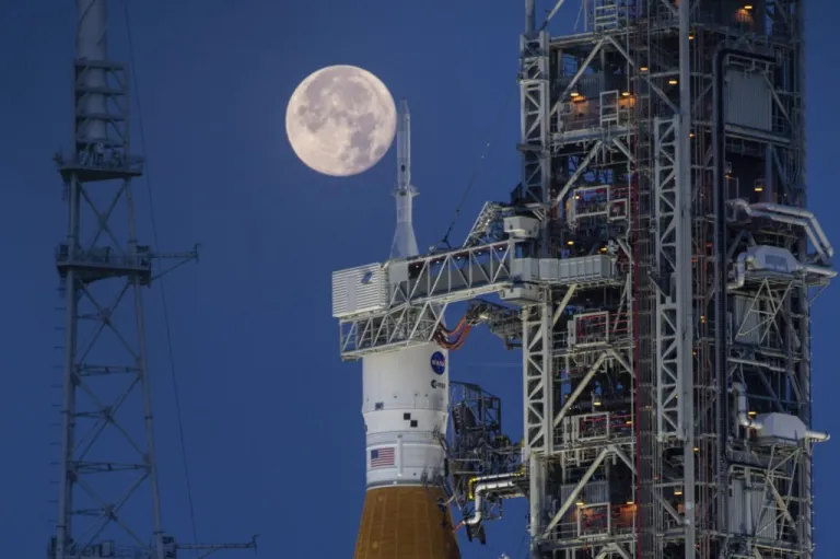 A full moon is seen behind the Artemis I Space Launch System and Orion spacecraft, atop the mobile launcher, are prepared for a wet dress rehearsal to practice timelines and procedures for launch
