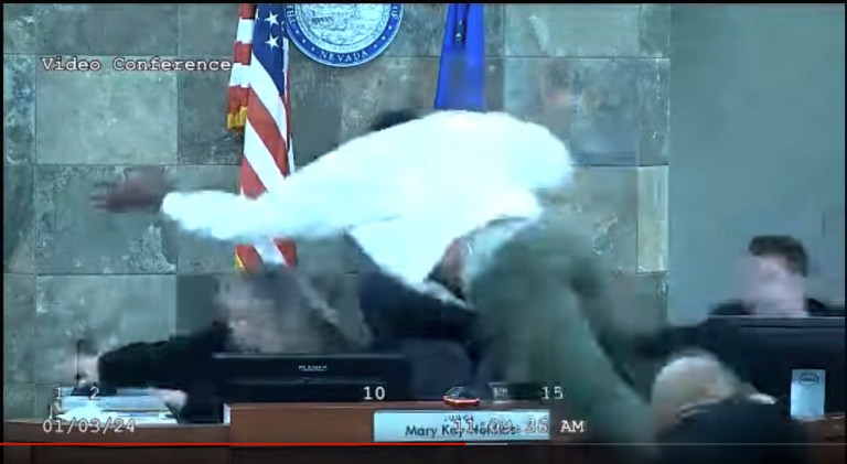 In this image from video provided by the Clark County District Court, a defendant identified by court officials and records as Deobra Redden is seen launching over the desk of Judge Mary Kay Holthus during his sentencing in a felony battery case on Wednesday, Jan. 3, 2024, in Las Vegas. Authorities said the judge suffered minor injuries while a courtroom marshal suffered a bleeding gash on his forehead and a dislocated shoulder. 