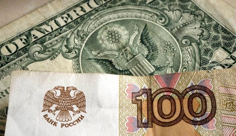 One hundred rubles banknote is pictured in front of a one US dollar banknote, Gelsenkirchen, Germany, Monday, April 25, 2022.
