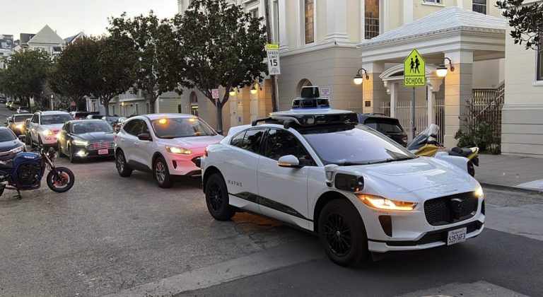 A Waymo driverless taxi stops on a street in San Francisco.