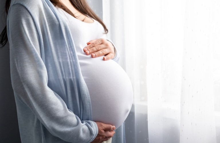 Side view pregnant woman with big belly advanced pregnancy in hands.