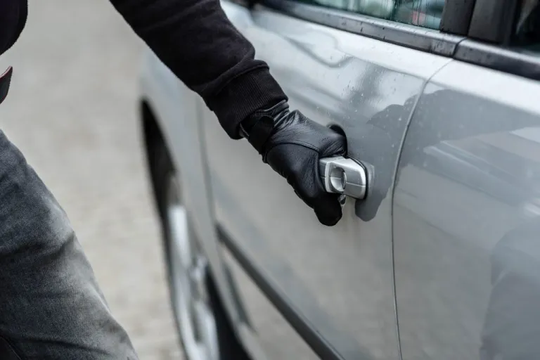 A hand with a leather glove grabbing a car door handle.