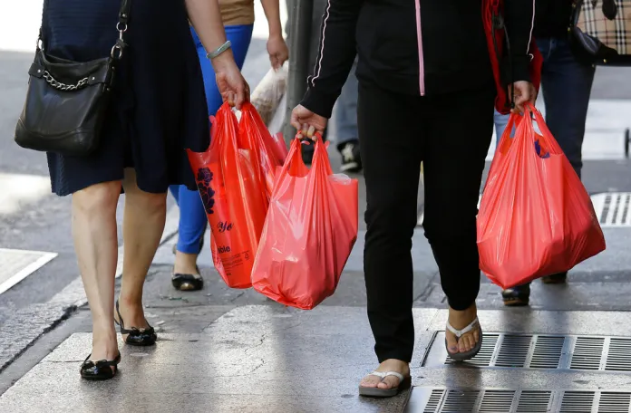 Women walk with plastic bags.