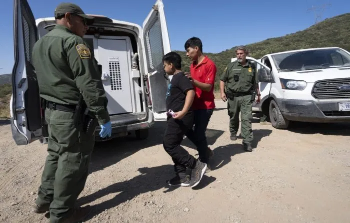 Border Patrol agents lead a group of migrants seeking asylum towards a van to be transported and processed, Wednesday, June 5, 2024, near Dulzura, Calif. President Joe Biden on Tuesday unveiled plans to enact immediate significant restrictions on migrants seeking asylum at the U.S.-Mexico border as the White House tries to neutralize immigration as a political liability ahead of the November elections.(AP Photo/Gregory Bull)