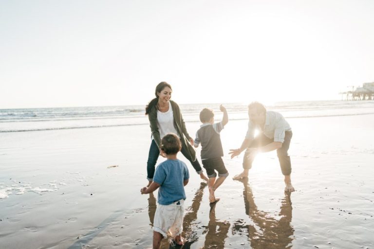 Parents playing with kids on the beach.
