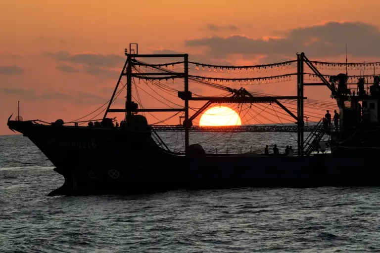 The sun rises while a suspected Chinese militia ship blocks Philippine coast guard ship.