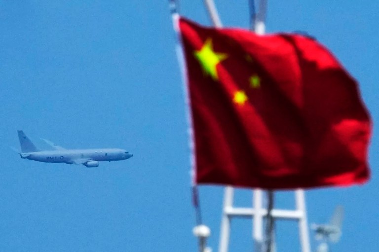 A U.S. Navy plane passes by a Chinese flag.