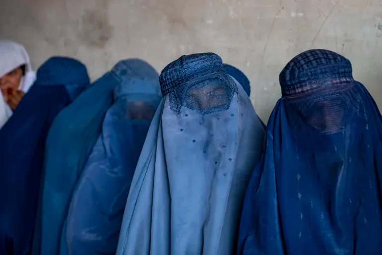 Afghan women wait to receive food rations.