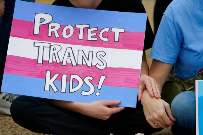 A protester holds a poster calling for lawmakers to protect trans children