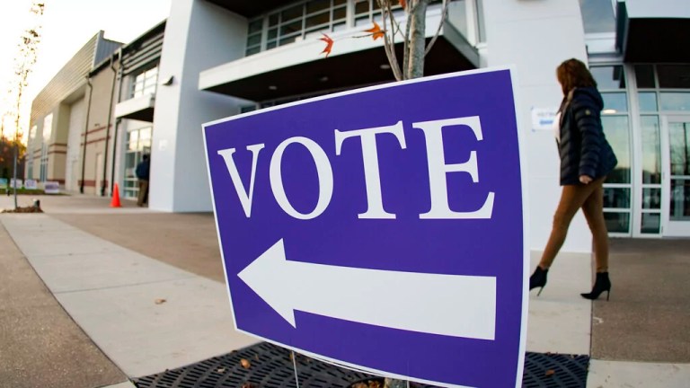 Voters walk past the sign pointing them to the polling location for in person voting in the general election, Tuesday, Nov. 8, 2022, in Cranberry Township, Pa.