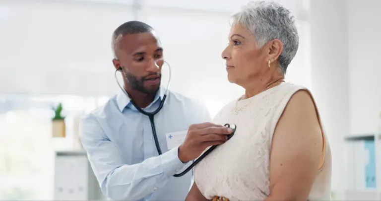 A physician checking a patient's heart with a stethoscope.