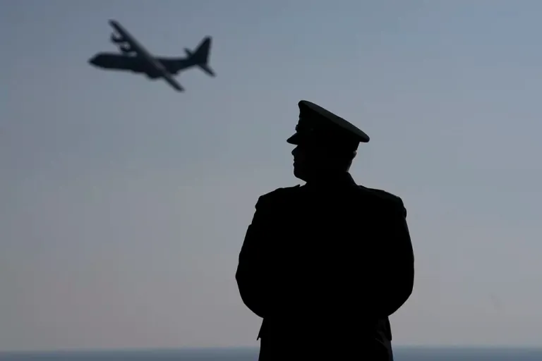 A participant watches as a plane flies past during a ceremony near Colleville-sur-Mer Normandy, Thursday, June 6, 2024. World War II veterans from across the United States as well as Britain and Canada are in Normandy this week to mark 80 years since the D-Day landings that helped lead to Hitler's defeat. (AP Photo/Laurent Cipriani)
