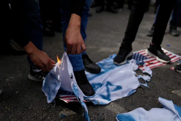 Palestinian activists burn IsraelI and U.S. flags during a protest marking the one year anniversary of the Israel Hamas war, in the West Bank city of Ramallah, Monday, Oct. 7, 2024. (AP Photo/Nasser Nasser)